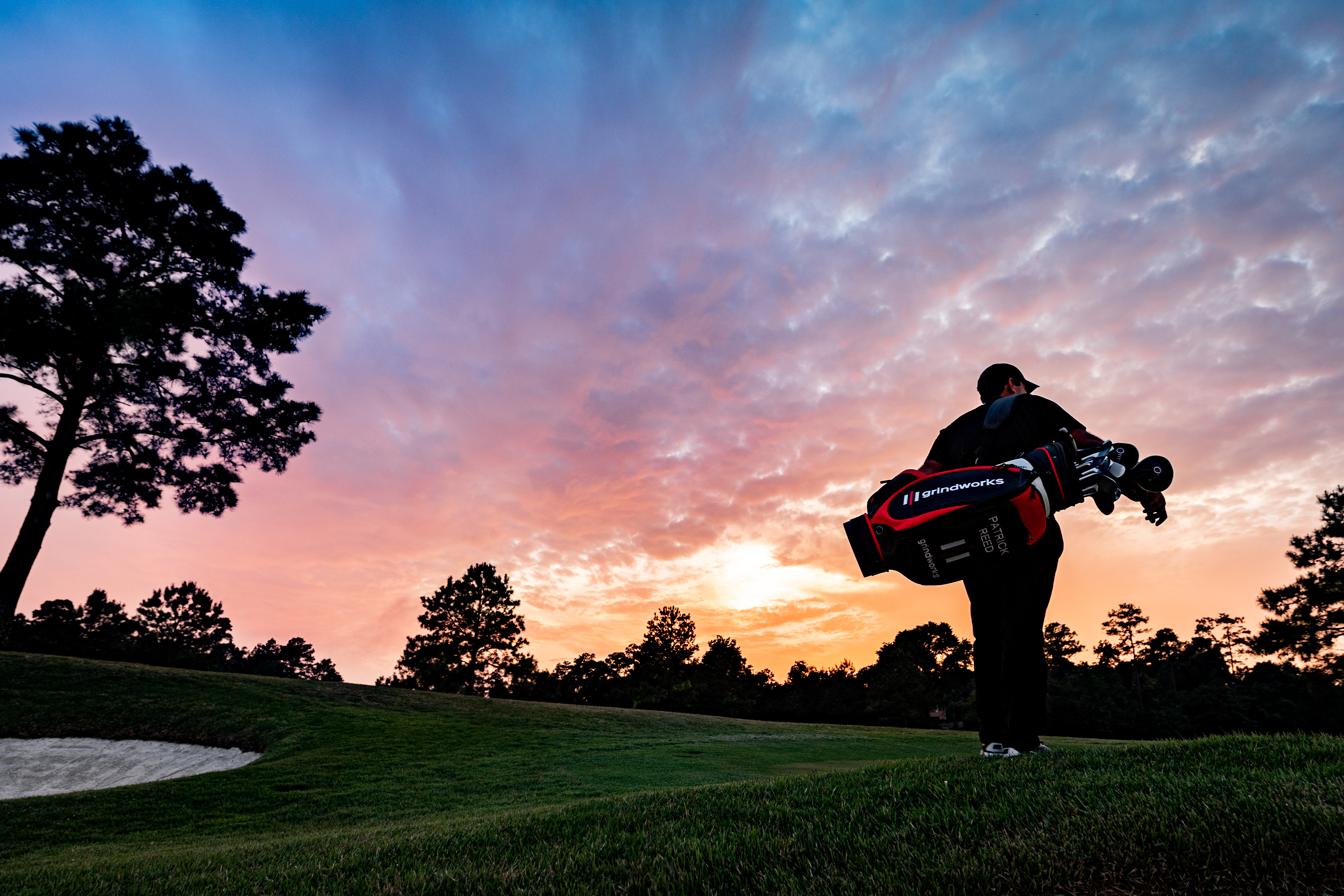 Patrick Reed walking off the green with his golf bag at sunset